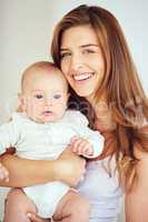A beautiful, loving and caring mother holding baby, smiling and looking happy with new born. Single blonde parent or young mom showing love and care for her infant, bonding and smiling together