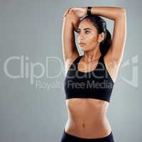 Stretching reduces the risk of injury. Studio shot of an athletic young woman posing with her arms raised against a grey background.