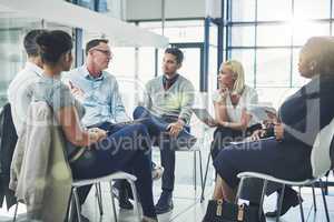Modern business people in an informal team building discussion or business talking session. Team leader, manager or supervisor talking to a group of employees or colleagues on new workflow management