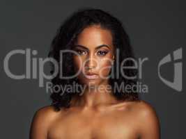 Naturally beautiful and glowing with confidence. Portrait of an attractive young woman posing shirtless and against a dark background in the studio.