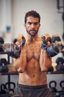 Working on his upper body strength. a handsome young man working out with kettle bells in the gym.