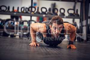 It takes power and perseverance. Full length shot of a handsome young man doing pushups while working out in the gym.
