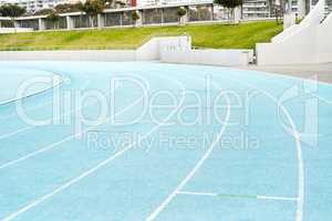 The calm before the storm. an empty athletic track field in a stadium during the day.