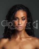 Comfortable in my own skin. Portrait of an attractive young woman posing alone shirtless and against a dark background in the studio.