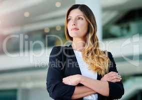 She knows exactly where she wants to be. an attractive young businesswoman looking thoughtful while standing with her arms crossed in a modern office.