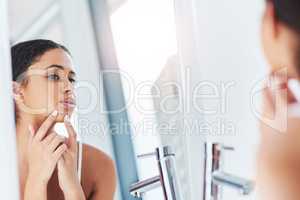 Popping and squeezing wont get rid of the problem. a beautiful young woman squeezing a pimple in the mirror.