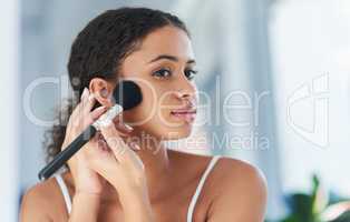 Add a dash of magic to each day. a young woman applying makeup to her cheeks in the bathroom at home.