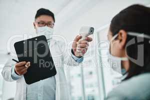 Doctor scanning the temperature of a patient for corona with a digital thermometer. Health care professional consulting with a concerned female about flu symptoms during the covid virus pandemic