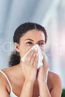 Guess which season I hate the most. an attractive young woman blowing her nose in the bathroom at home.