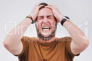 This pressure is too much. Studio shot of a handsome young man looking stressed out against a grey background.