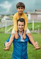 Spending some time with my little champ. Portrait of a cheerful father carrying his young son on his shoulders outdoors.