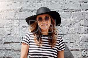 Suns out, let the good times roll. Portrait of an attractive young woman posing against a brick wall outdoors.