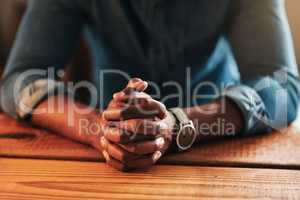 Quiet, calm and spiritual man praying while sitting with his hands folded alone at home. Close up praying, hopeful and religious, Christian male saying a daily prayer in the morning at a table