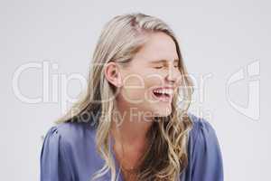 Laughter will make you forget about your problems. Studio shot of an attractive young woman laughing while standing against a grey background.