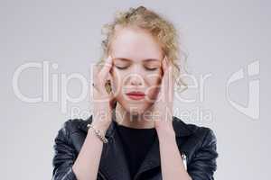 Why did this headache have to start now. a young woman holding her head while suffering from a headache against a grey background.