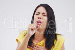 Under the weather. Studio shot of an attractive young woman coughing against a grey background.