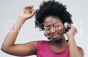 Shes loving this song. Studio shot of an attractive young woman dancing against a grey background.