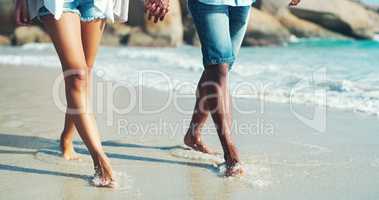 The course of true love is a seashore stroll. an unrecognizable affectionate couple taking a walk at the beach.