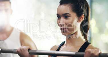 Unhealthy doesnt exist in her vocabulary. an attractive young sportswoman working out with a barbell in a gym.