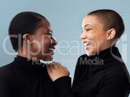 Our humor is the same. Studio shot of two beautiful young women holding each other while standing against a grey background.