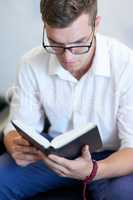 Knowledge will always be power. a handsome young businessman reading his bible at work.