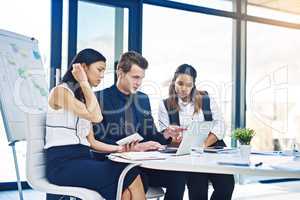 Pointing out the important details. a group of young businesspeople having a discussion while using a laptop in a modern office.