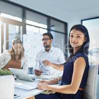 We offer the best services in the industry. Portrait of an attractive young businesswomen sitting in her office while her colleagues are having a discussion in the background.