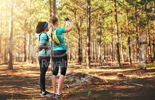 Take nothing but memories with you. two sporty young woman taking pictures while out in nature.