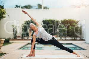 Keep calm and do yoga. a young woman doing yoga poolside.