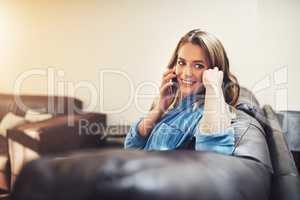 Id love some company on my day off. a relaxed young woman using a smartphone on the sofa at home.