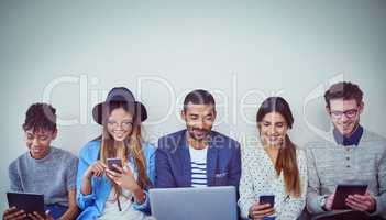 Were best friends with online networking. Studio shot of a group of young businesspeople using wireless technology while sitting in line against a grey background.