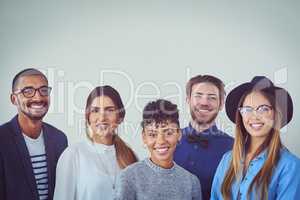 We shine when we work as a team. Studio portrait of a group of young businesspeople smiling while standing against a grey background.