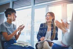 We always come up with best ideas when working together. a group of young businesswomen giving their colleague a round of applause during a meeting at work.