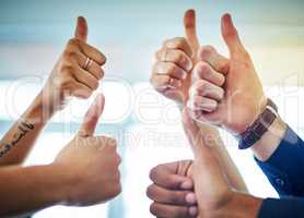 Thumbs up to the occasion. a group of unrecognizable businesspeople showing thumbs up in a modern office.