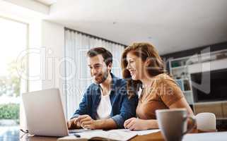 That looks like a great idea, we should try that too. a young couple watching online videos together while doing their monthly budget at home.