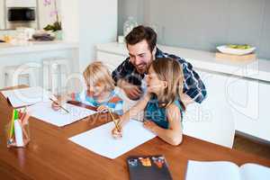 Helping them discover all their hidden talents. a young father helping his two small children with their homework at home.