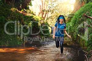Exercise and have fun while doing it. a sporty young running through a stream of water in nature.