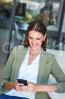 Regular contact keeps her clients happy. a young businesswoman using a mobile phone in a modern office.