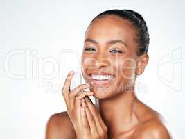 Natural shine. Studio portrait of an beautiful young woman applying skin moisturizer to her face while standing next to a white background.