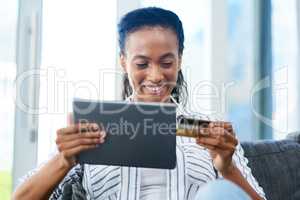 E-commerce has changed the way we shop. a young woman using a credit card and digital tablet at home.