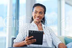 Spending her free time at home. a young woman using a digital tablet at home.