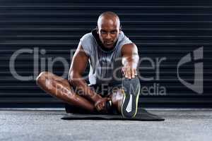 Its not easy, no one said it would be. a sporty young man stretching his legs as part of his exercise routine.