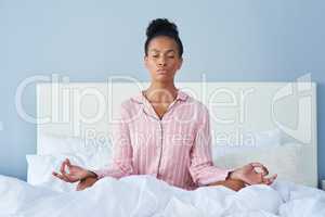 Always take time to meditate. an attractive young woman meditating in bed at home.