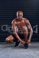 Im ready to sweat some more. a sporty young man tying his shoelaces in the middle of his exercise routine.