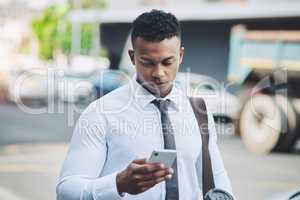 Technology enables him to navigate the concrete jungle. a handsome young businessman using a cellphone in the city.