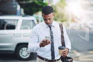 He does business on the move. a handsome young businessman using a cellphone in the city.