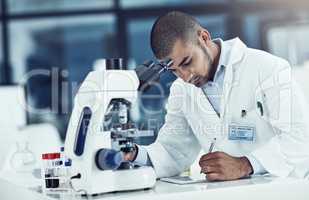 Serious male scientist writing on a tablet for an online phd research paper in a lab. Laboratory worker working on health data for a science journal. Medical professional analyzing test results