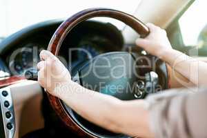 Hands of a driver on a steering wheel in a car for travel, driving or taking a roadtrip. Take a drive in a taxi, cab or with a rideshare service. Closeup of a limousine chauffeur practicing safety