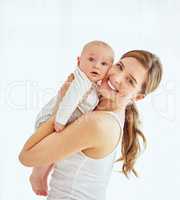 Portrait of a happy young mother hugging her cute baby boy at home, bonding and enjoying parenthood. Single parent being playful and affectionate, embracing precious moments with her new born child