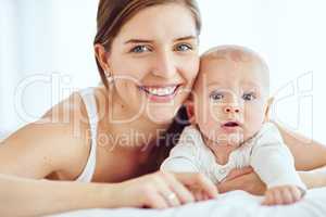 Portrait of happy and loving mother bonding with her cute baby boy at home while enjoying parenthood. Single parent being playful and affectionate, embracing precious moments with her newborn child